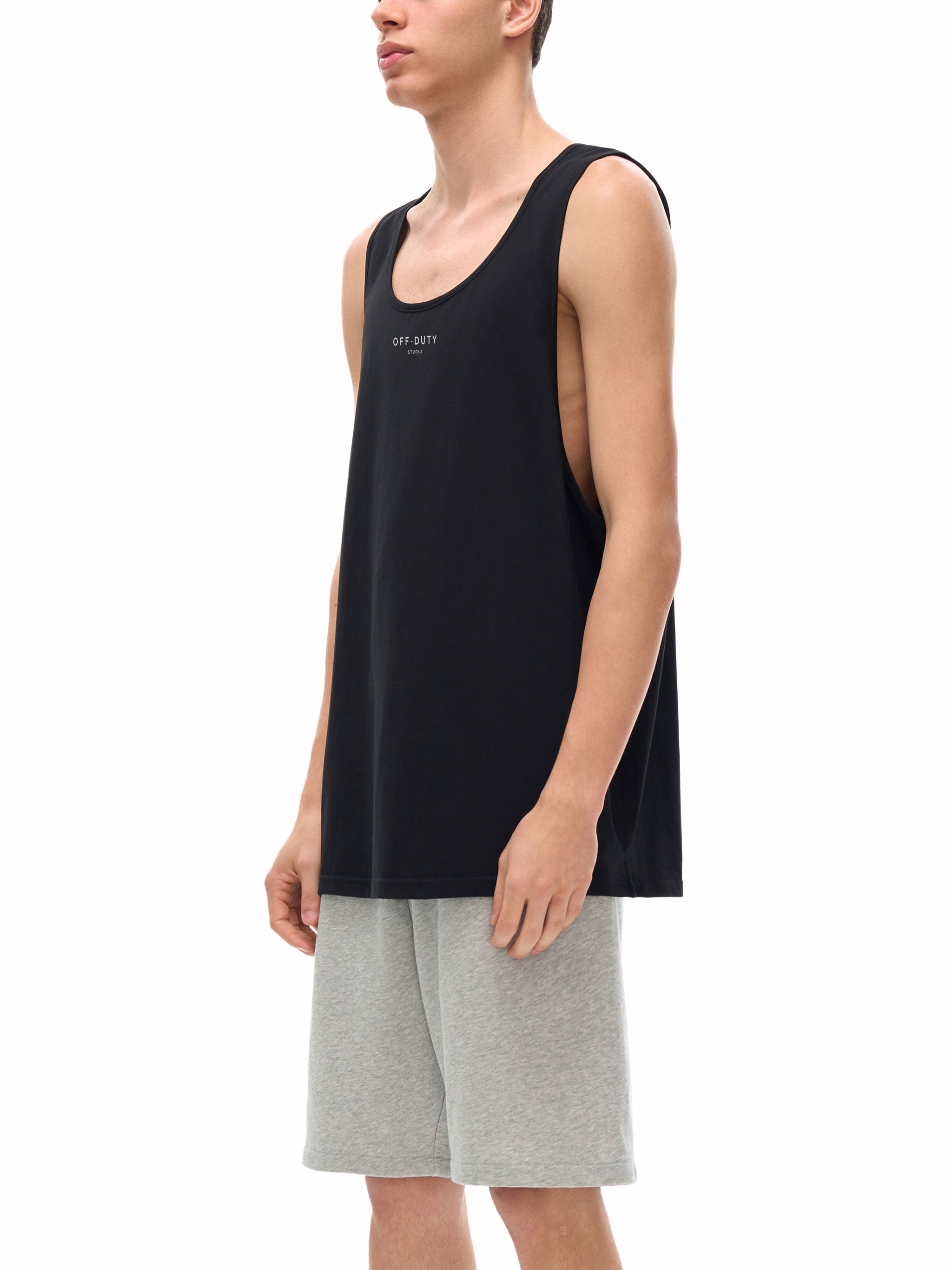 Person wearing a black tank top and gray shorts on a white background